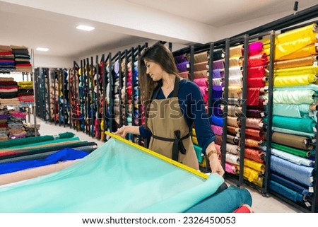 brazilian store seller measuring fabric for sale inside store Royalty-Free Stock Photo #2326450053
