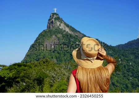 Tourism in Rio de Janeiro. Back view of tourist woman looking at Christ the Redeemer statue on the top of Corcovado mountain, Rio de Janeiro, Brazil.