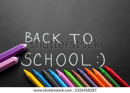 Back to school background with color crayones. black background. Handwritten text with white chalk on a blackboard. Colorful. Concept of education. Hand-drawn simple font.