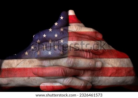 Close up of man's praying hands with American flag overlay isolated on black background Royalty-Free Stock Photo #2326461573