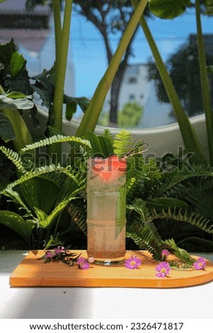 A vertical shot of a tropical cocktail served on the wooden salver with an exotic background Royalty-Free Stock Photo #2326471817