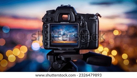 Camera on the background of city lights and sunset. Concept on the topic of photography and photo technology.