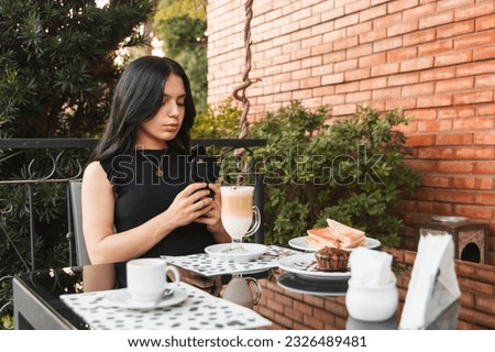Beautiful girl taking pictures of her breakfast with her smart phone in an outdoor cafe