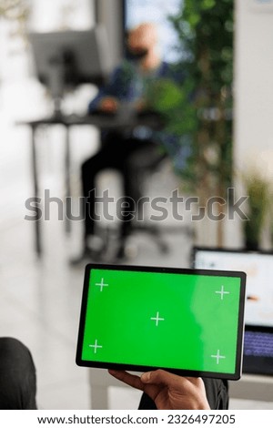 Employee holding tablet with chroma key screen while working in business office. Executive manager using digital device with green touchscreen while analyzing financial report
