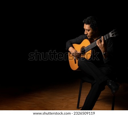 hispanic man playing guitar, guitarist on a black background studio shot, latin professional guitar player Royalty-Free Stock Photo #2326509119