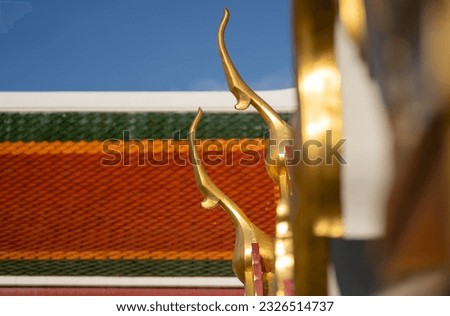 Wat Ratchanatdaram, Bangkok, Thailand. Chofas – temple decoration,  roof finials, decoration, golden against blue sky.