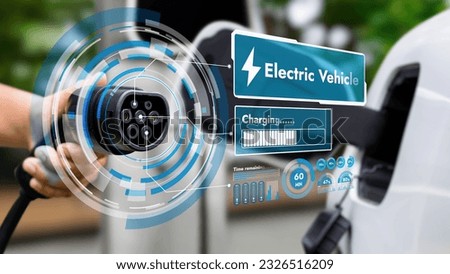 Focus hand pointing EV charger in front of camera display smart battery status hologram in blurry background. Electric car charger using clean energy reducing CO2 emission.Peruse