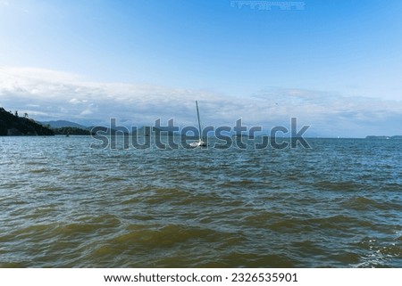 A sailboat over the Paraty's beach. The calms water help the little boat to sail freely over the Atlantic Ocean. The harbor is very calm and very windy.