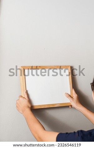 woman hanging blank frame on a wall