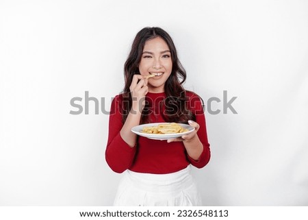 Image of smiling young Asian girl eating french fries isolated on white background Royalty-Free Stock Photo #2326548113