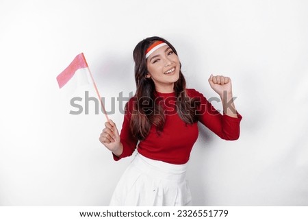 Excited young Asian woman celebrate Indonesian independence day holding the Indonesian flag isolated on white background Royalty-Free Stock Photo #2326551779