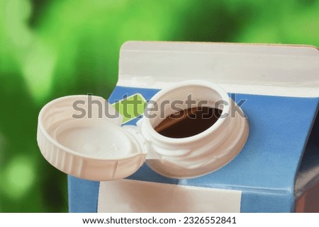 Bottle tethered cap is together with milk package or bottle. Concept image of environment friendly recycling. Royalty-Free Stock Photo #2326552841
