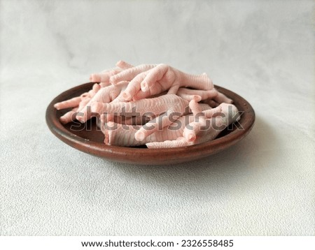A plate of raw chicken claws on a white background