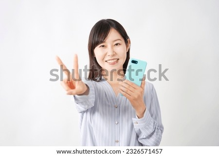 Asian middle aged woman with the smartphone peace sign gesture in white background round
