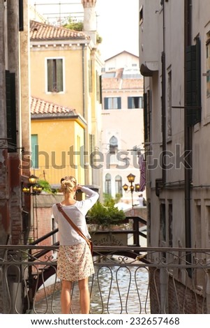 A woman takes a picture of a canal, Venice, Italy