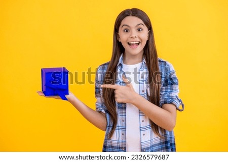 surprised teen girl holding shopping box on background. teen girl after successful shopping. teen girl with shopping box isolated on yellow. teen girl shopping with present in studio