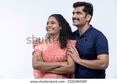 Portrait of smiling Indian couple with arms around on white background Royalty-Free Stock Photo #2326584589