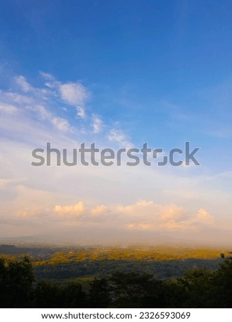 photo of cloudy blue sky from mountain track with green colour from trees in the forest