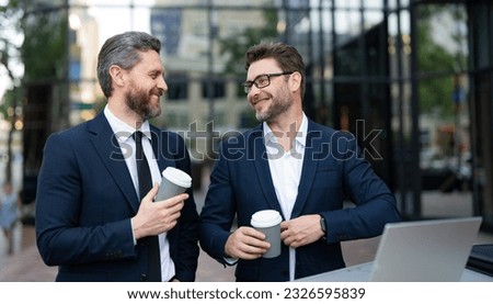 photo of smiling trader men freelancing online having coffee. two trader men freelancing online.