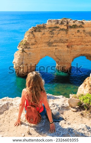 Woman enjoying beautiful view of natural arch in atlantic ocean- travel destination, summer holiday concept- Algarve in Portugal Royalty-Free Stock Photo #2326601055