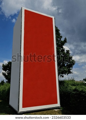 metal structure shape of a block with stretched sails for placing printed advertising. An empty canvas is suitable for creating an inscription. red rectangle in the countryside by road, pillar
