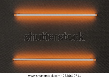 Orange neon bulb on white wall, LED screen background.