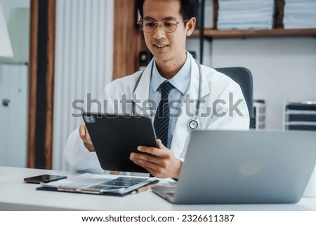 Asian medical doctors specialist in white lab coats , research or online consultation, discussing at meeting on video conference on laptop at desk in medical industry.