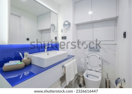 Interior of apartment standard modern bathroom with toilet bowl and glass shower cabin