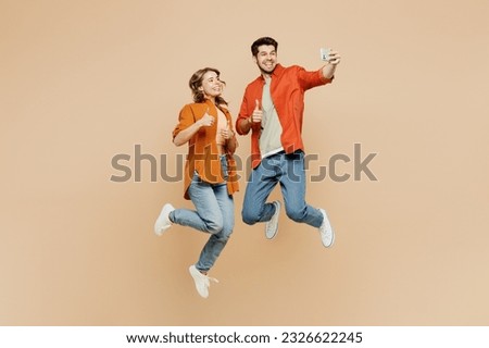 Full body young couple two friends family man woman wear casual clothes together doing selfie shot on mobile cell phone post photo on social network jump high isolated on pastel plain beige background Royalty-Free Stock Photo #2326622245