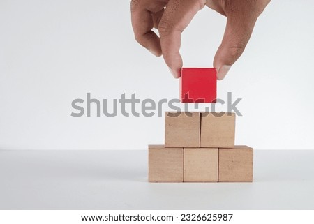 Hand stacking red wooden cube on table to pyramid shaped with copy space for put text,word,logo or infographic icon perfect for  flat lay top view mock-up item,business concept.