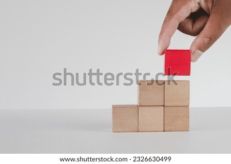 Hand stacking red wooden cube as step stair on table with copy space for put text,word,logo or infographic icon perfect for flat lay top view mock-up item,business concept.