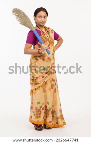 Young woman of indian origin with a sweeping broom Royalty-Free Stock Photo #2326647741
