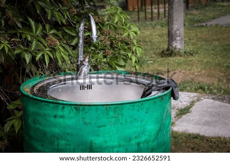 Outdoor faucet and sink in the green barrel. For washing hands and gardening.