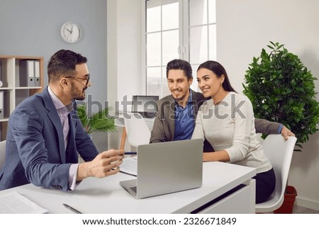 Portrait of happy caucasian couple sitting with a business broker or insurance agent showing project on a laptop screen. Clients having consultation with a man realtor or financial advisor at office. Royalty-Free Stock Photo #2326671849