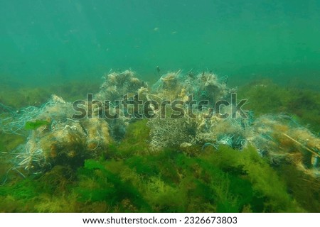 Lost fishing net lies on seabed in green algae Ulva on bright sunny day in sun glare in Black sea, Ghost gear pollution of Seas and Ocean, Black Sea, Odessa, Ukraine Royalty-Free Stock Photo #2326673803
