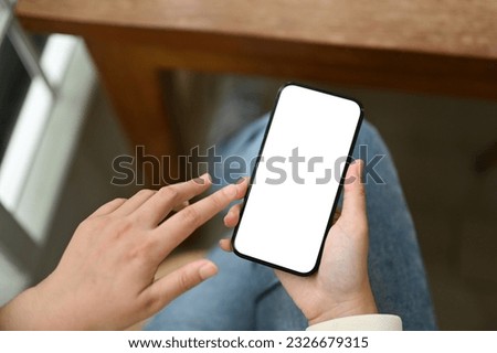 Close-up image of a young Asian woman using her smartphone while sitting at a table in a coffee shop. smartphone white screen mockup