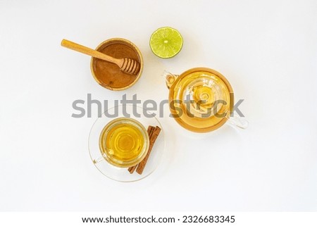 Top view of a cup of tea with ginger root, lime, cinnamon and teapot on white background. Health drink concept.	
