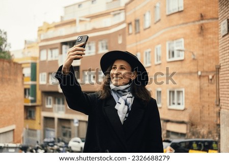 Cheerful young tourist woman taking photo in old european city