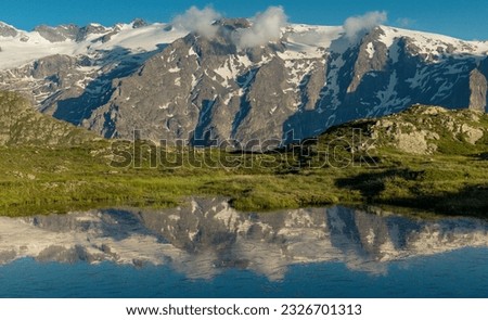 view of the peaks and glaciers of La Meije from the Ecrins massif with reflection in a high altitude lake in summer in the Alps in France in Oisans