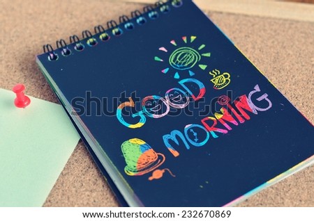 Notebook with text 'Good Morning' on the cover on a wooden table.