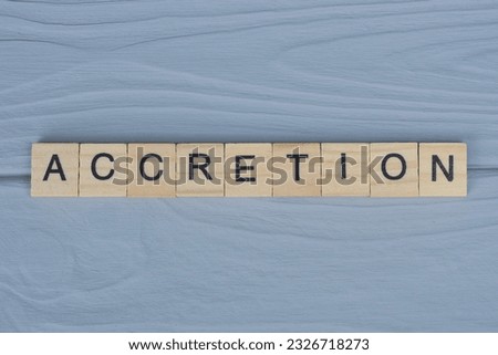 text the word accretion from brown wooden small letters with black font on an gray table Royalty-Free Stock Photo #2326718273