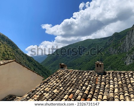 tiled roof of old houses in Italy against the backdrop of high mountains