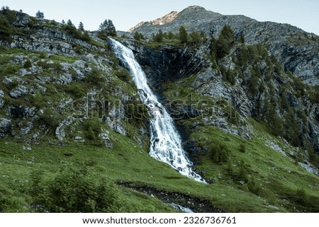 big waterfall in the green mountains of the alps