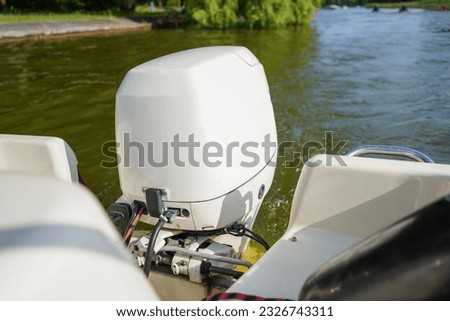Outboard engine. Close up of white outboard motor on the lake. Boat swimming on the river. Royalty-Free Stock Photo #2326743311