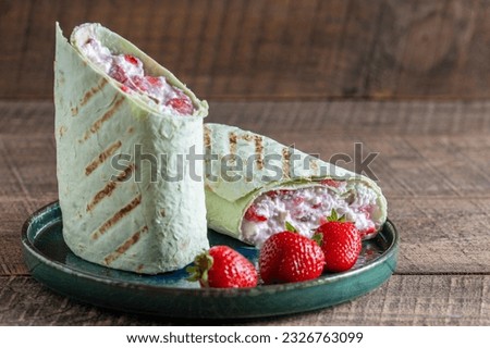Pita bread wrapped with cottage cheese and red strawberries , close up