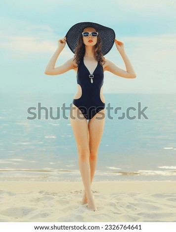 Summer vacation, beautiful young woman in bikini swimsuit and straw hat on the beach on sea coast background