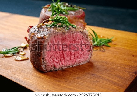 Modern style traditional fried dry aged angus beef filet medaillons natural wrapped with bacon and served on a wooden design board  Royalty-Free Stock Photo #2326775015