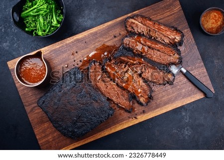 Modern style traditional smoked barbecue wagyu beef brisket with baby broccoli served as top view on a wooden design cutting board with Louisiana sauce  Royalty-Free Stock Photo #2326778449