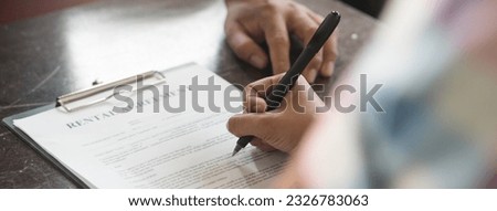 Close up hand of Tenant signing rental document with realtor agent after agreement is deal.