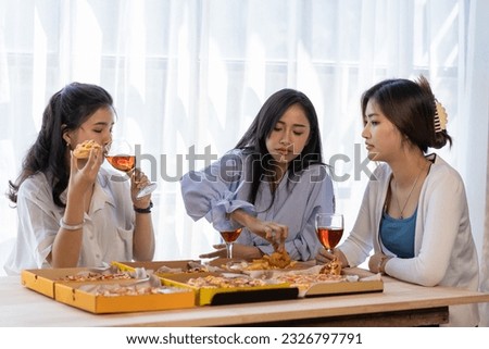 Three Asian girls have a fun pizza party at home at lunchtime.